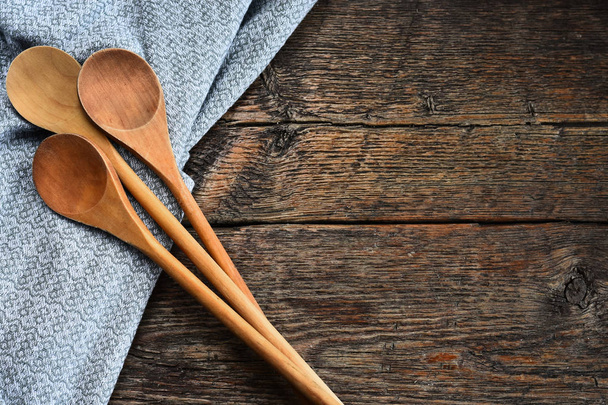 An image of wooden mixing spoons and colorful table cloth on an old style country kitchen table top.  - Фото, изображение