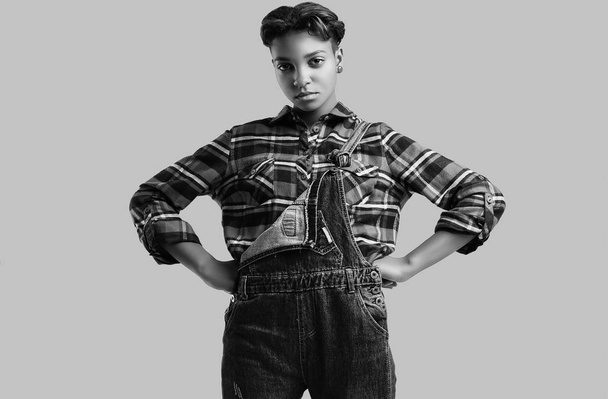 Studio のカラフルな背景にポーズ格子縞のシャツとデニムつなぎでショートヘアのグラマー エレガントな黒内気な少女の官能的な肖像画 - 写真・画像