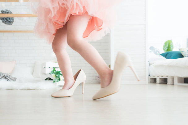 Cute little girl with her mothers shoes at home. - Foto, immagini
