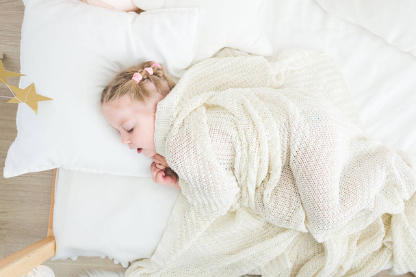 Cute little girl sleeping covered in white blanket. - 写真・画像