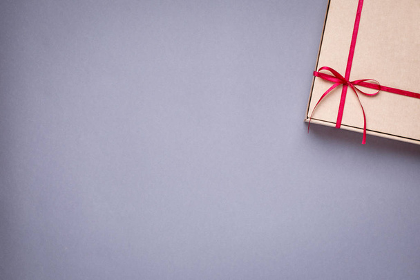 Gift in box with burgundy satin ribbon on a gray background top view - 写真・画像