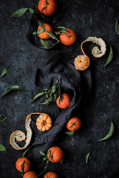 Top view of fresh mandarin oranges or tangerines with leaves on textured dark background.  - Photo, image