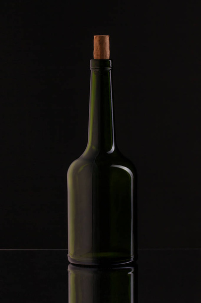 Wine bottle on a black background. Soft beautiful highlights on the bottle, with reflection. - Foto, afbeelding
