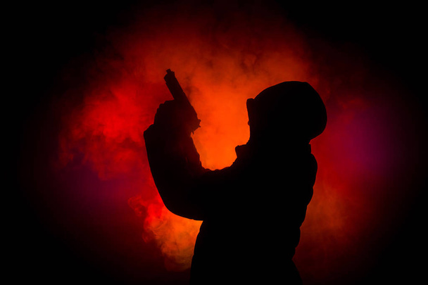 ダークで攻撃する準備ができてのピストルを持った男のシルエット トーン霧の背景や危険な山賊持株銃手。武器のテーマの装飾が施されたテロリストを撮影 - 写真・画像