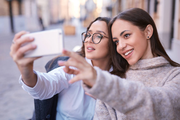 two beautiful women making selfie by the phone in the central part of city - Φωτογραφία, εικόνα