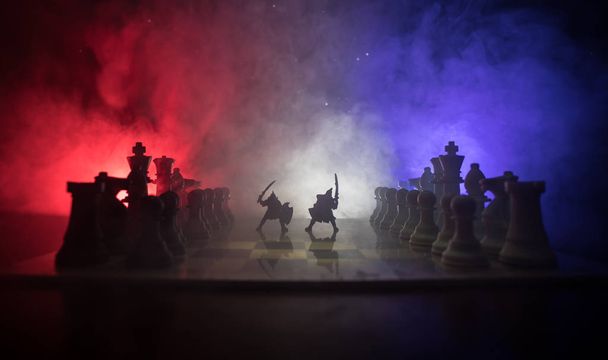 Cena de batalha medieval com cavalaria e infantaria no tabuleiro de xadrez. Conceito de jogo de tabuleiro de xadrez de ideias de negócios e concorrência e ideias de estratégia Figuras de xadrez em um fundo escuro com fumaça e nevoeiro
. - Foto, Imagem