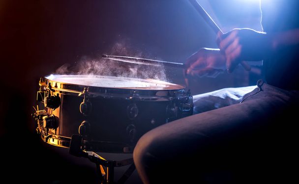 man playing the snare drum on a beautiful colored background, the concept of musical instruments - Photo, Image