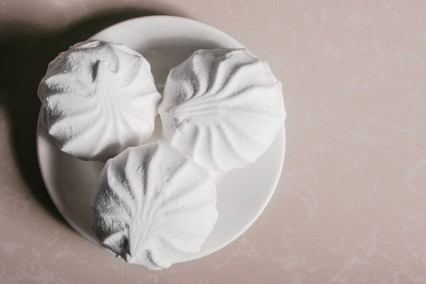 Τρεις νόστιμο γλυκό επιδόρπιο λευκά marshmallows Ζέφυρος σε ένα κοντινό πλάνο πιατάκι. Χώρο αντίγραφο - Φωτογραφία, εικόνα