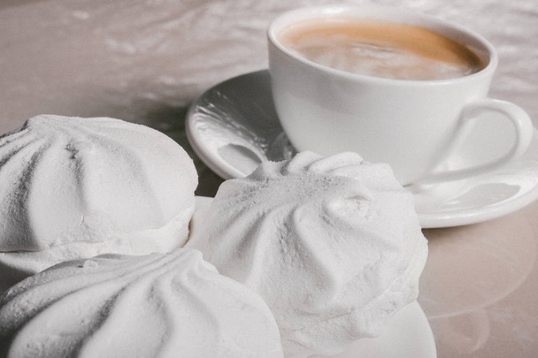 Чашка свежего кофе, американо и три вкусных сладких десерта с белым зефиром на блюдце крупным планом. Копирование пространства
 - Фото, изображение
