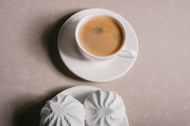 Una tazza di caffè fresco, americano e tre deliziosi marshmallow dolci bianchi su un primo piano piattino. Copia spazio
 - Foto, immagini
