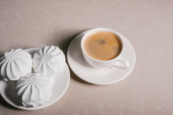 Kuppi tuoretta kahvia, americano ja kolme herkullista jälkiruoka valkoista vaahtokarkkia lautasella lähikuva. Kopioi tila
 - Valokuva, kuva