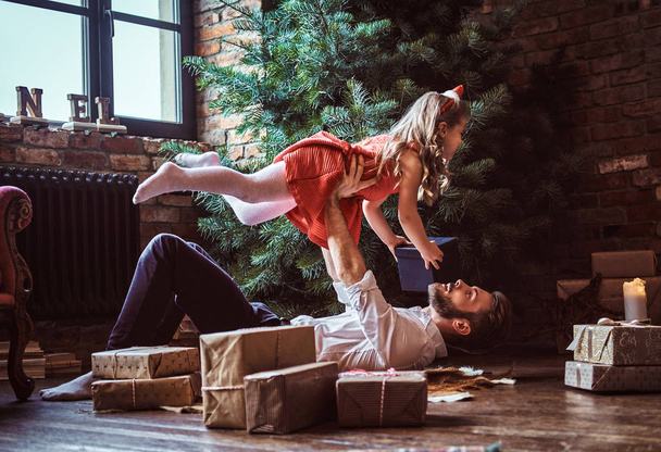 Батько і дочка веселитися разом під час лежав на підлозі, в оточенні подарунки біля ялинки - Фото, зображення