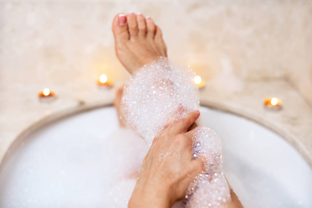 Woman legs in bath foam. Relaxation in spa. - Фото, зображення