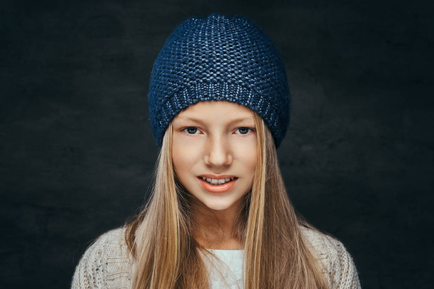 Портрет усміхненої дівчини-підлітка з світлим волоссям у зимовому капелюсі та светрі
 - Фото, зображення