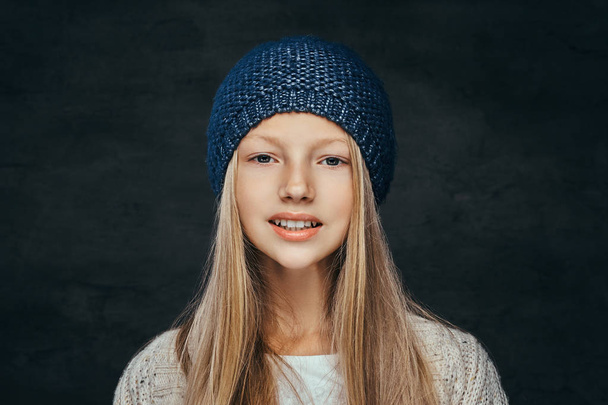 Portrait d'une adolescente souriante aux cheveux blonds portant un chapeau et un pull d'hiver
 - Photo, image