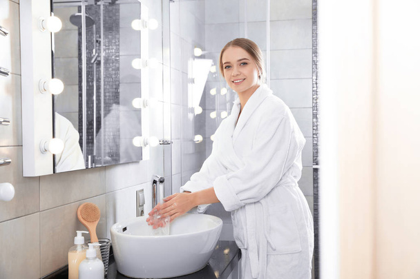 Young woman washing hands in bathroom. Using soap - Valokuva, kuva
