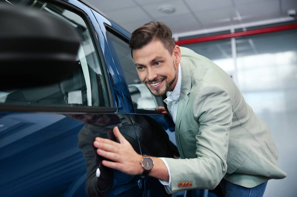 Man near new car in modern auto dealership - Zdjęcie, obraz