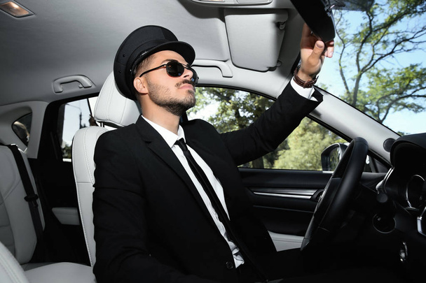 Young handsome driver adjusting interior mirror in luxury car - Photo, image