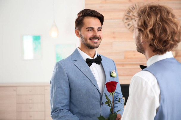 Happy newlywed gay couple with flower at home - Fotó, kép