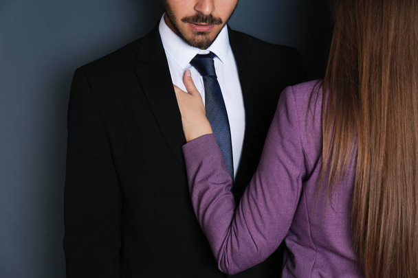 Woman molesting her male colleague on dark background, closeup. Sexual harassment at work - Fotoğraf, Görsel