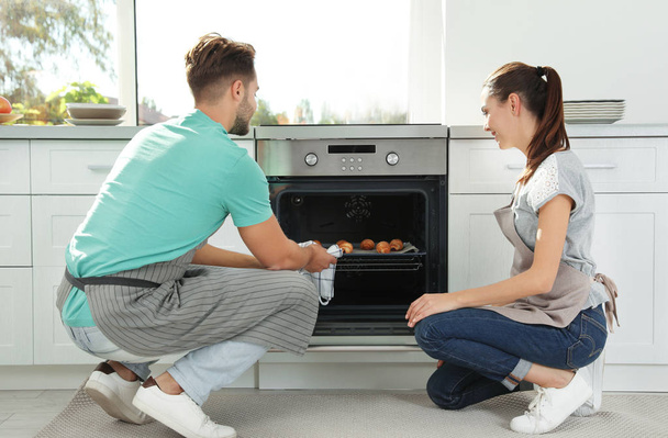 Young couple baking croissants in oven at home - Foto, Imagem