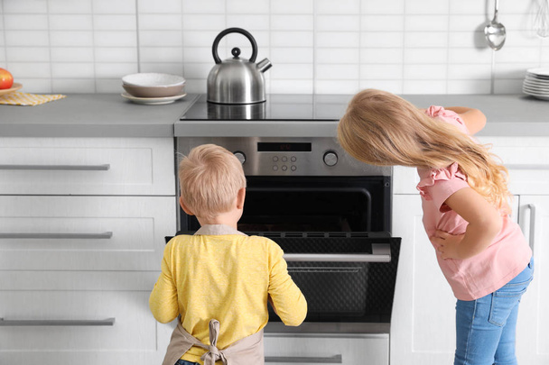 Little kids baking something in oven at home - 写真・画像