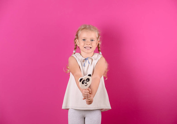 Cute little girl with candy on color background - Foto, Bild