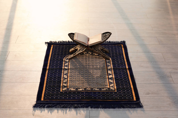 Rehal with open Quran on Muslim prayer mat indoors - 写真・画像