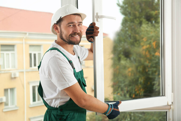 Construction worker installing new window in house - 写真・画像