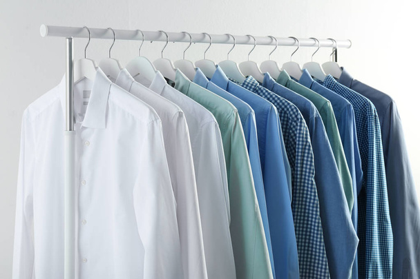 Men's clothes hanging on wardrobe rack against white background - Foto, afbeelding