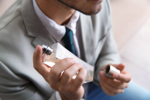 Businessman applying perfume on blurred background, closeup - Фото, зображення