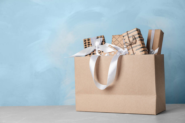 Paper shopping bag with handles full of gift boxes on table. Mock up for design - Foto, immagini