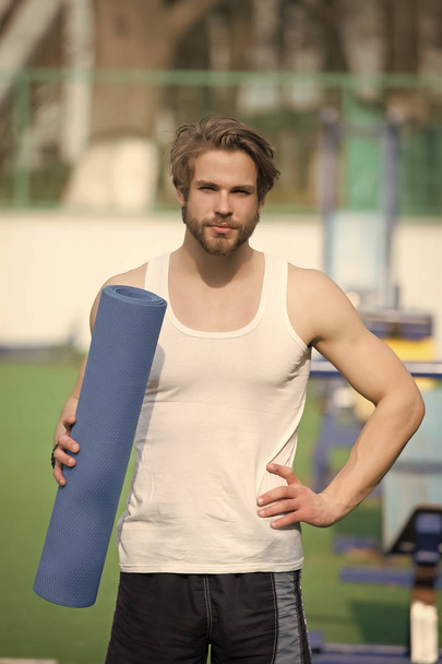 Sportsman with blue yoga mat in strong hands - Zdjęcie, obraz