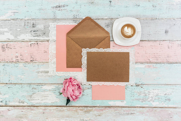 flat lay with greeting card mockup and envelope with pink peony flower and cup of coffee on vintage background - Фото, изображение