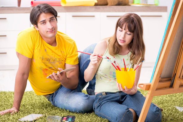 Νεαρό ζευγάρι απολαμβάνει ζωγραφική στο σπίτι - Φωτογραφία, εικόνα