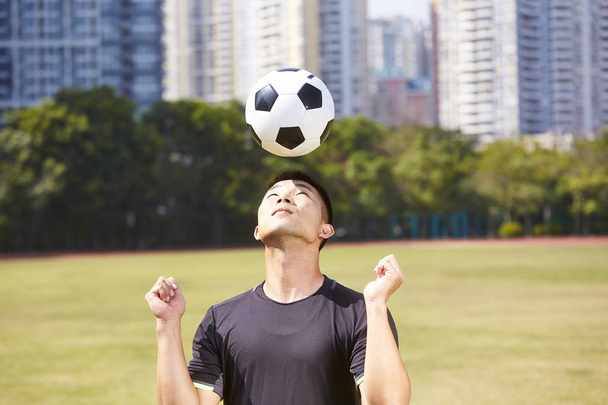 asian soccer football player practicing ball skill on outdoor field - 写真・画像