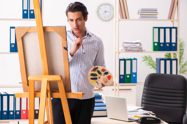 Νέος όμορφος υπάλληλος απολαμβάνει τη ζωγραφική στο γραφείο  - Φωτογραφία, εικόνα
