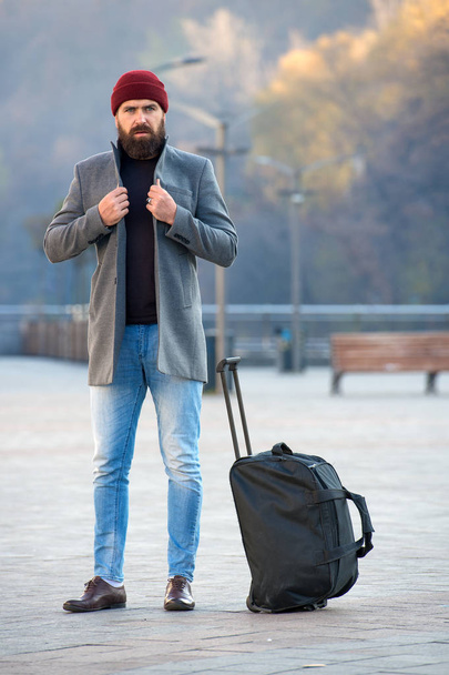 Man bearded hipster travel with big luggage bag wait for taxi bring him to hotel. Travel tips. Traveler with suitcase arrive travel destination. Hipster ready enjoy travel. Looking for accommodation. - Photo, image