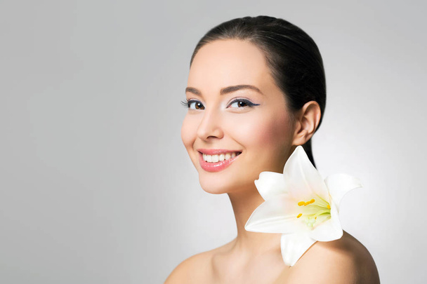 Portrait of brunette beauty in light makeup with white lily flower - Fotó, kép