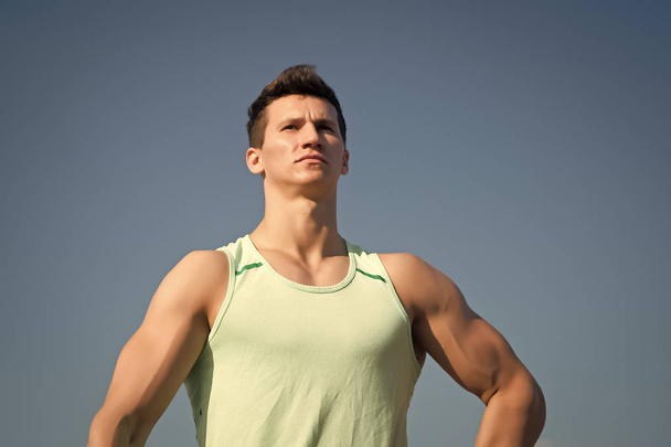 Man bodybuilder posing on blue sky - Zdjęcie, obraz