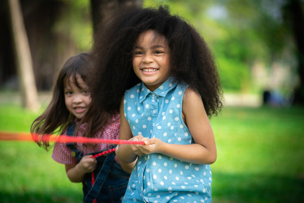 Gelukkige kinderen spelen touwtrekken en plezier tijdens de zomer kamperen in het park. Kinderen recreatie concept. - Foto, afbeelding