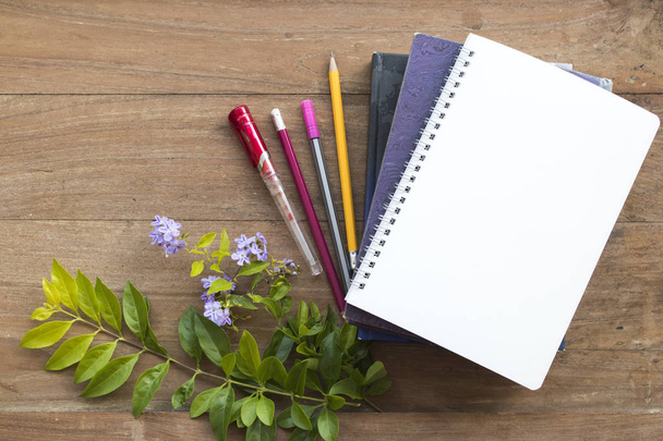 libro diccionario, cuaderno, estacionario para el estudio de los estudiantes con flor púrpura sobre fondo de madera
 - Foto, Imagen