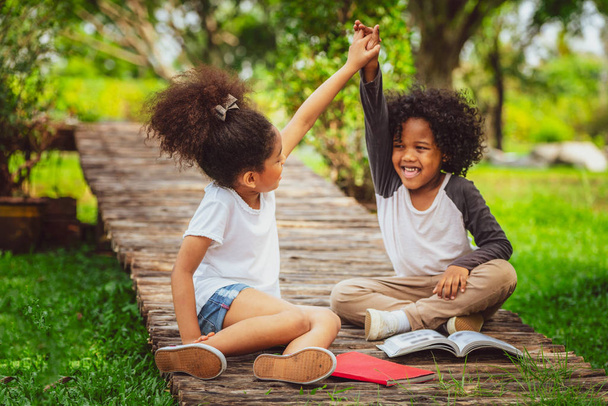 glückliche kleine Jungen und Mädchen im Park. zwei afrikanisch-amerikanische Kinder zusammen im Garten. - Foto, Bild