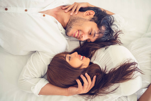 Счастливая молодая пара расслабляется в домашней спальне после пробуждения по утрам
. - Фото, изображение