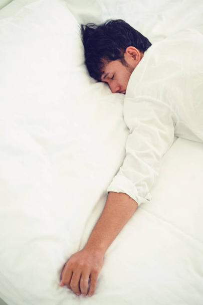 junger Mann schläft in weißer Bettwäsche im Schlafzimmer. - Foto, Bild