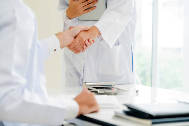 成功と医療スタッフのチームワークを示す別の医者に握手を与える病院医師. - 写真・画像