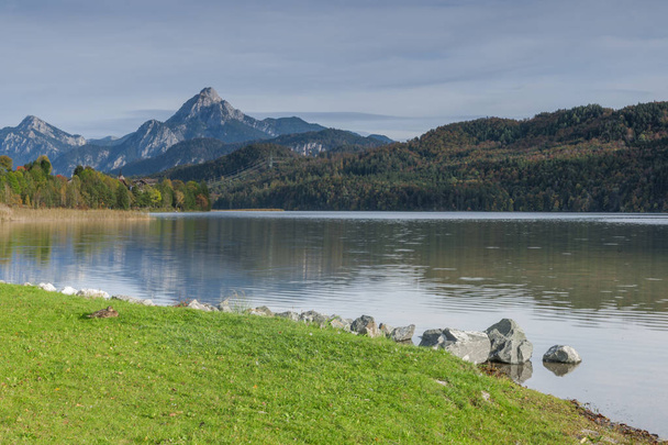 Широкоугольный пейзаж над озером Вайсензее с первыми предгорьями высоких Альп на заднем плане, недалеко от города Фуессен
. - Фото, изображение