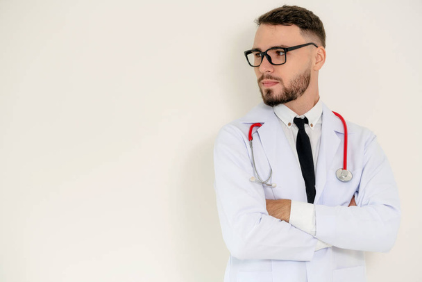 Young handsome doctor with arms crossed standing on white background. Medical and healthcare concept. - Фото, зображення