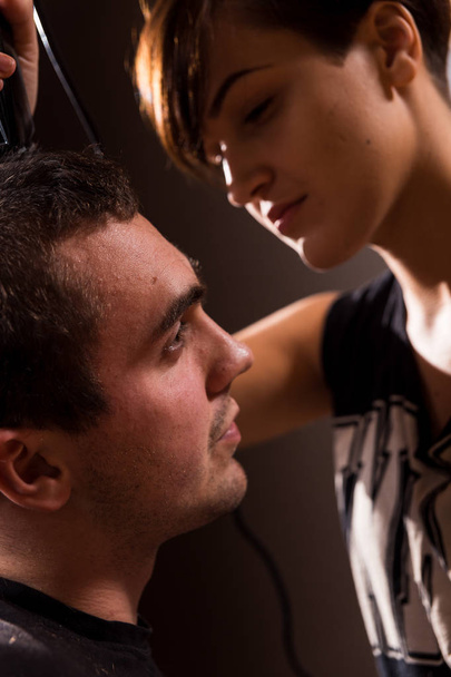 Young punk girl cuts her boyfriend using clippers. - Photo, Image