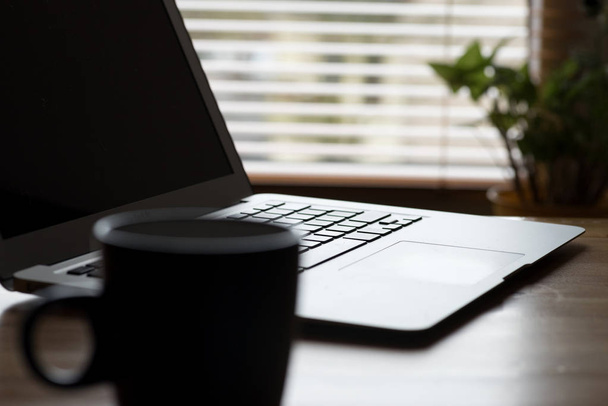 Un computer portatile e una tazza di caffè su un tavolo in ufficio
 - Foto, immagini
